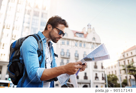 Where am I. Cropped shot of a handsome young man looking at a map while touring a foreign city. 90517143