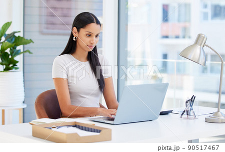 Focused and ready to tackle this day. Shot of a young businesswoman using her laptop at work. Focused and ready to tackle this day. Shot of a young businesswoman using her laptop at work. 90517467