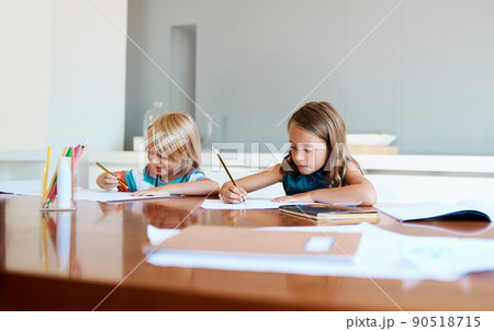 School is cool and they already know it. Shot of two adorable young children doing their homework together at home. School is cool and they already know it. Shot of two adorable young children doing their homework together at home. 90518715