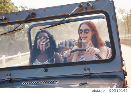 Fun is our fuel. Cropped shot of two laughing woman driving down a dirt road. 90519145
