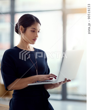 Money is in technology nowadays. Cropped shot of a young businesswoman holding her laptop while standing in the office. 90519233