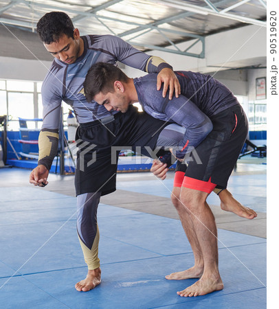 Attack and counter. Full length shot of a jiu jitsu sensei sparring with one of his students during a class. 90519620