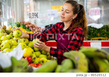 Young saleswoman puts apples on the counter 90520512