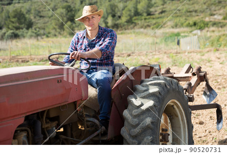 Positive man working on farm tractor Positive man working on farm tractor 90520731