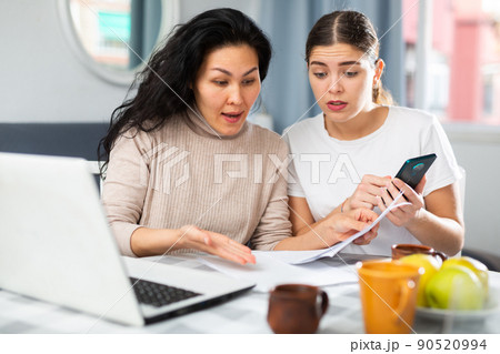Women trying to pay bills, using laptop and smartphone 90520994