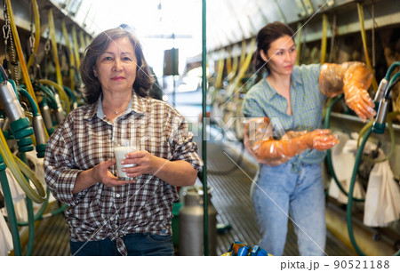 Woman with milk glass near milking line 90521188