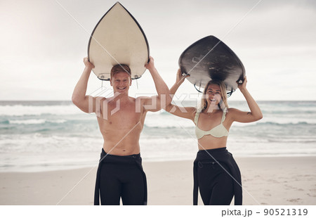 Another day, another opportunity to catch some waves. Shot of a couple out at the beach with their surfboards. 90521319