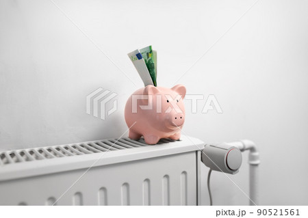 piggy bank with money on radiator at home piggy bank with money on radiator at home 90521561