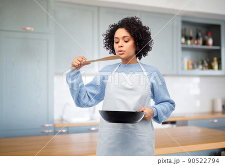 woman with frying pan tasting food in kitchen woman with frying pan tasting food in kitchen 90522794
