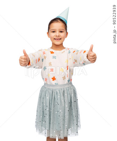 happy girl in birthday party hat showing thumbs up 90522939