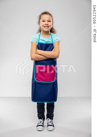 smiling little girl in apron with crossed arms 90522945