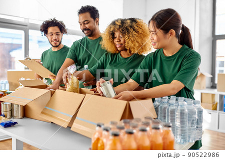 happy volunteers packing food in donation boxes happy volunteers packing food in donation boxes 90522986