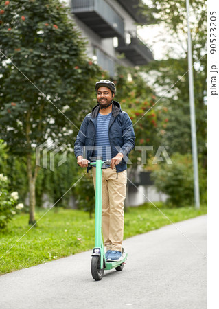 man in helmet riding electric scooter on street man in helmet riding electric scooter on street 90523205