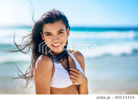 Having a little fun in the sun. Portrait of a beautiful young woman in a white bikini posing on the beach. 90523424