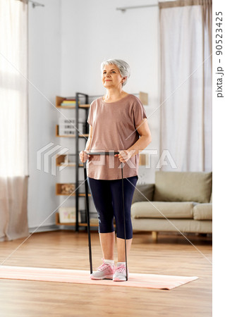 senior woman exercising with elastic band at home 90523425
