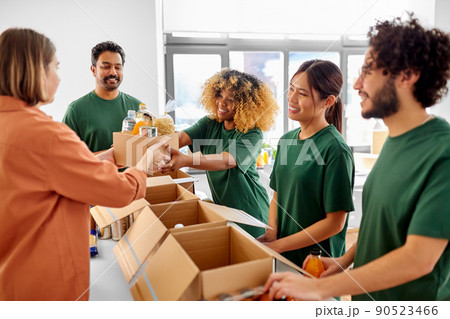 happy volunteers packing food in donation boxes 90523466