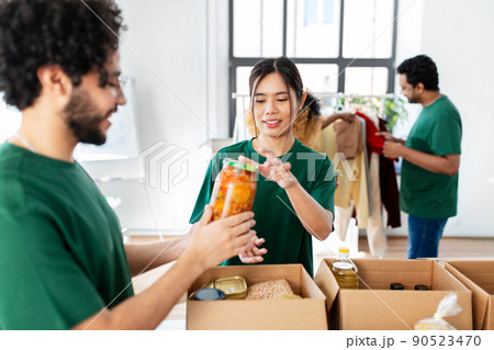 happy volunteers packing food in donation boxes 90523470