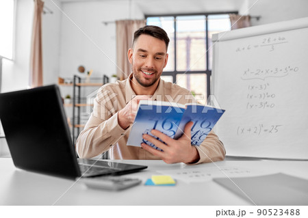 math teacher with laptop and book at home office 90523488