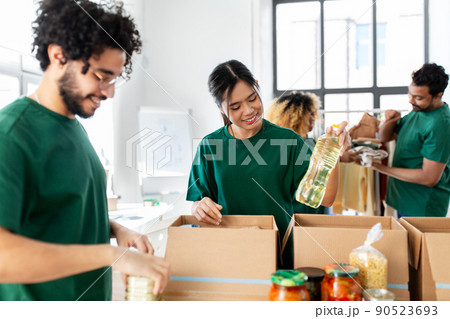 happy volunteers packing food in donation boxes happy volunteers packing food in donation boxes 90523693