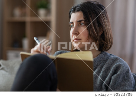 sad woman with diary sitting on sofa at home 90523709