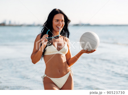 woman in bikini posing with volleyball on beach 90523730
