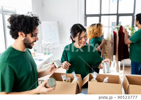 happy volunteers packing food in donation boxes happy volunteers packing food in donation boxes 90523777
