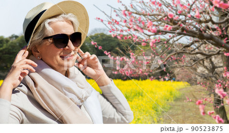 senior woman in sunglasses and hat over sakura senior woman in sunglasses and hat over sakura 90523875
