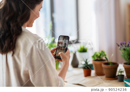 woman with smartphone photographing pot flowers woman with smartphone photographing pot flowers 90524236
