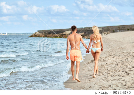happy couple walking along summer beach happy couple walking along summer beach 90524370