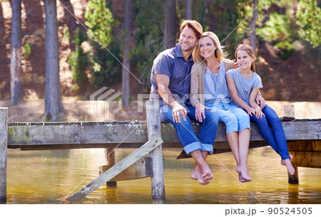 Family time is so precious. A happy family of three sitting together on the jetty at the lake. Family time is so precious. A happy family of three sitting together on the jetty at the lake. 90524505