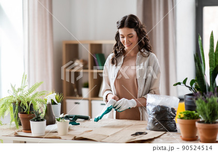 happy woman with gloves planting flowers at home 90524514