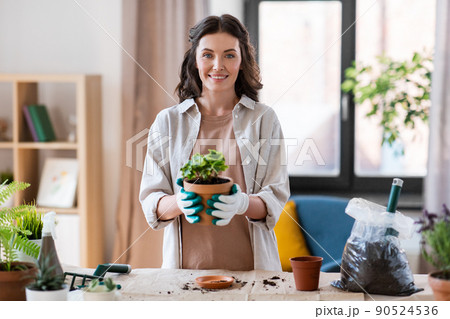 happy woman planting pot flowers at home 90524536
