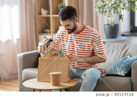 smiling man unpacking takeaway food at home smiling man unpacking takeaway food at home 90524538