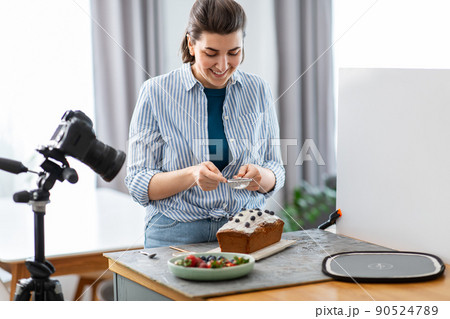 food blogger with camera icing cake in kitchen food blogger with camera icing cake in kitchen 90524789
