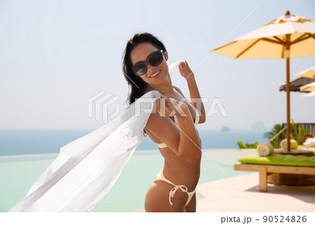 woman in bikini with pareo over infinity edge pool 90524826