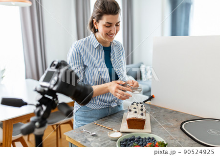 food blogger with camera icing cake in kitchen food blogger with camera icing cake in kitchen 90524925