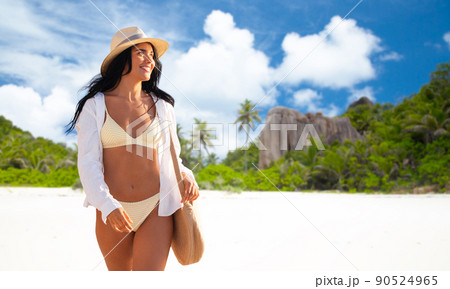 happy woman in bikini and shirt walking on beach 90524965