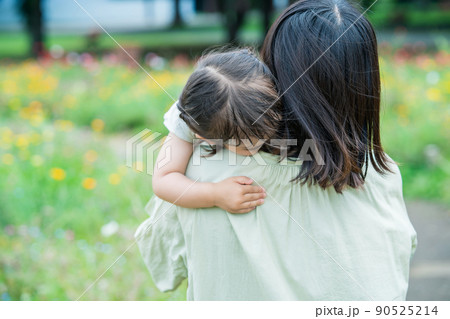 遊び疲れてお母さんに抱っこされる女の子 90525214