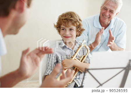 Supporting his talent. Shot of a cute little boy looking pleased as his father and grandfather cheer him on after playing the trumpet. Supporting his talent. Shot of a cute little boy looking pleased as his father and grandfather cheer him on after playing the trumpet. 90526595