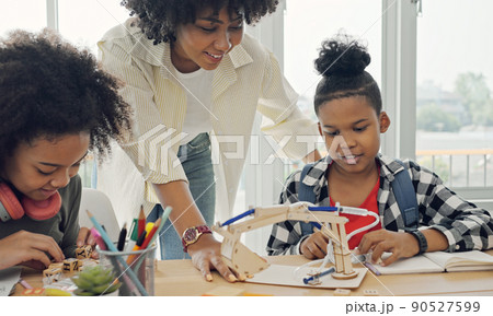 Classroom with diverse learners of happily African American students and teacher doing activities together. The teacher is teaching, guiding and talking to the children in diverse. 90527599