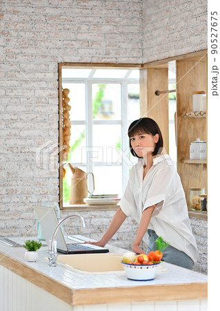 キッチンでパソコンの操作をする若い女性 キッチンでパソコンの操作をする若い女性 90527675
