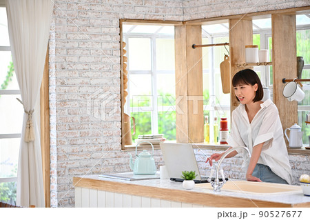 キッチンでパソコンの操作をする若い女性 キッチンでパソコンの操作をする若い女性 90527677