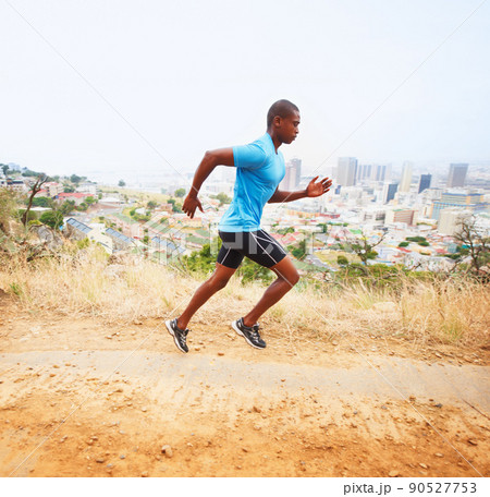 Ive gotta beat my time. A young man running along a nature trail with the city in the background. 90527753