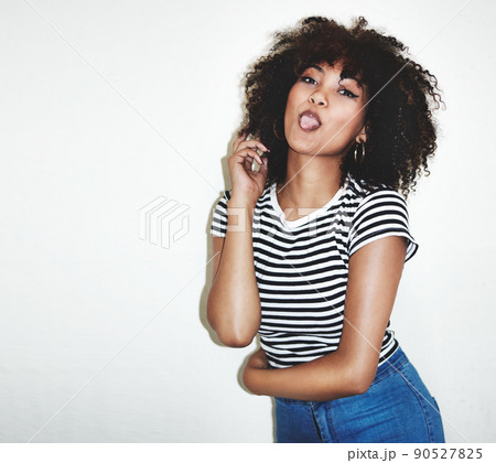 Shes charmingly cheeky. Studio shot of a young woman playfully sticking her tongue out against a gray background. 90527825