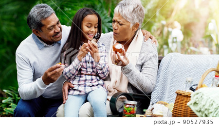 We always have healthy treats for her. Shot of a cheerful little girl sitting down on a bench with her grandparents at the park. We always have healthy treats for her. Shot of a cheerful little girl sitting down on a bench with her grandparents at the park. 90527935