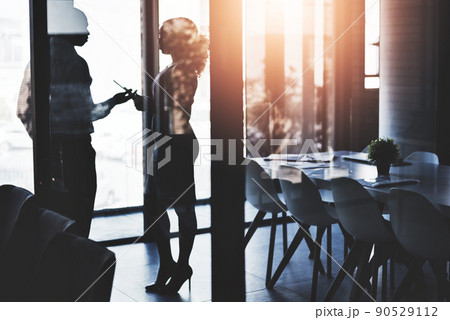 Enhancing business together. Silhouetted shot of two businesspeople having a discussion in an office. 90529112