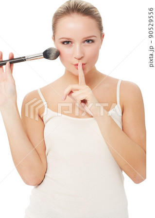 These are my beauty secrets.... A pretty woman putting a finger to her lips while applying blush to her face. These are my beauty secrets.... A pretty woman putting a finger to her lips while applying blush to her face. 90529556