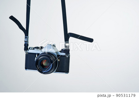 Film photography makes a comeback. Studio shot of a camera hanging by its strap. Film photography makes a comeback. Studio shot of a camera hanging by its strap. 90531179