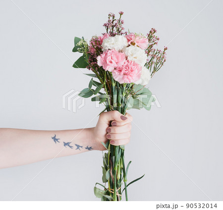 These flowers represents pure love and admiration. Studio shot of an unrecognizable woman holding a bunch of flowers against a grey background. 90532014