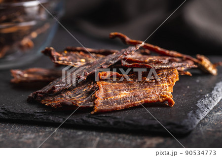 Beef jerky meat. Dried sliced meat on cuting board. 90534773